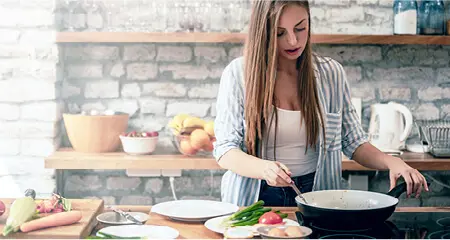 Young woman cooking a healthy meal on electric stove top