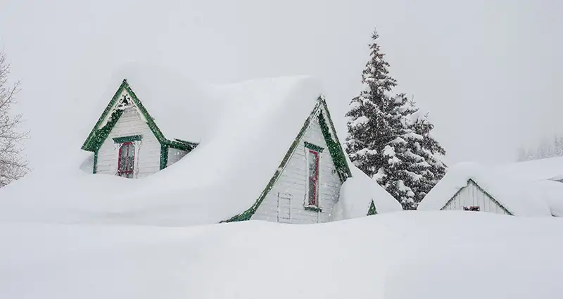 Casa cubierta de nieve durante una tormenta de invierno.