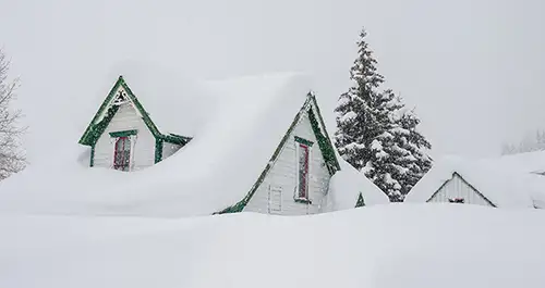 Casa cubierta de nieve durante una tormenta de invierno.