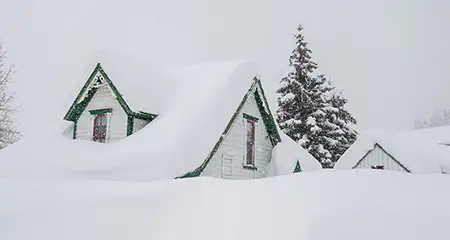 Casa cubierta de nieve durante una tormenta de invierno.