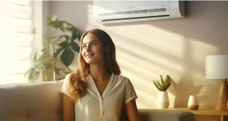 Woman switching on air conditioner while sitting on sofa at home