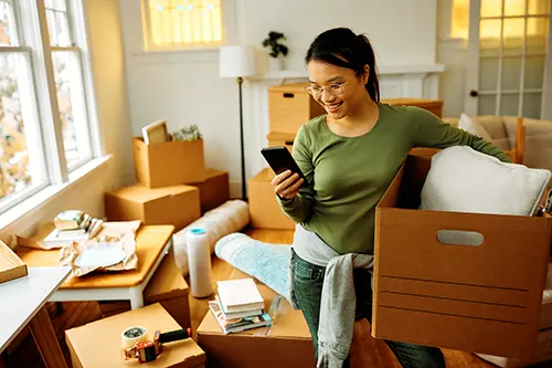 woman-moving-into-new-home-holding-box-and-phone