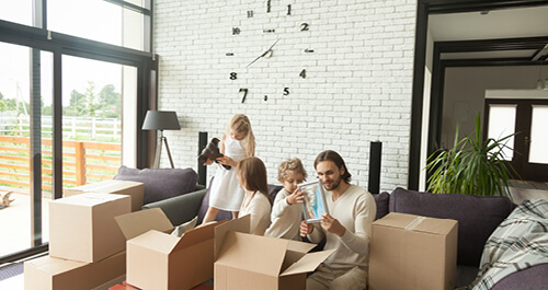Kids unpacking boxes with their parents in modern living room
